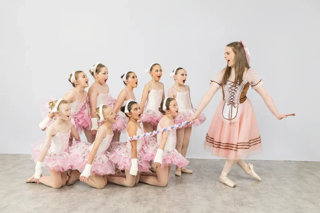 Ballet instructor leading young dancers in pink tutus