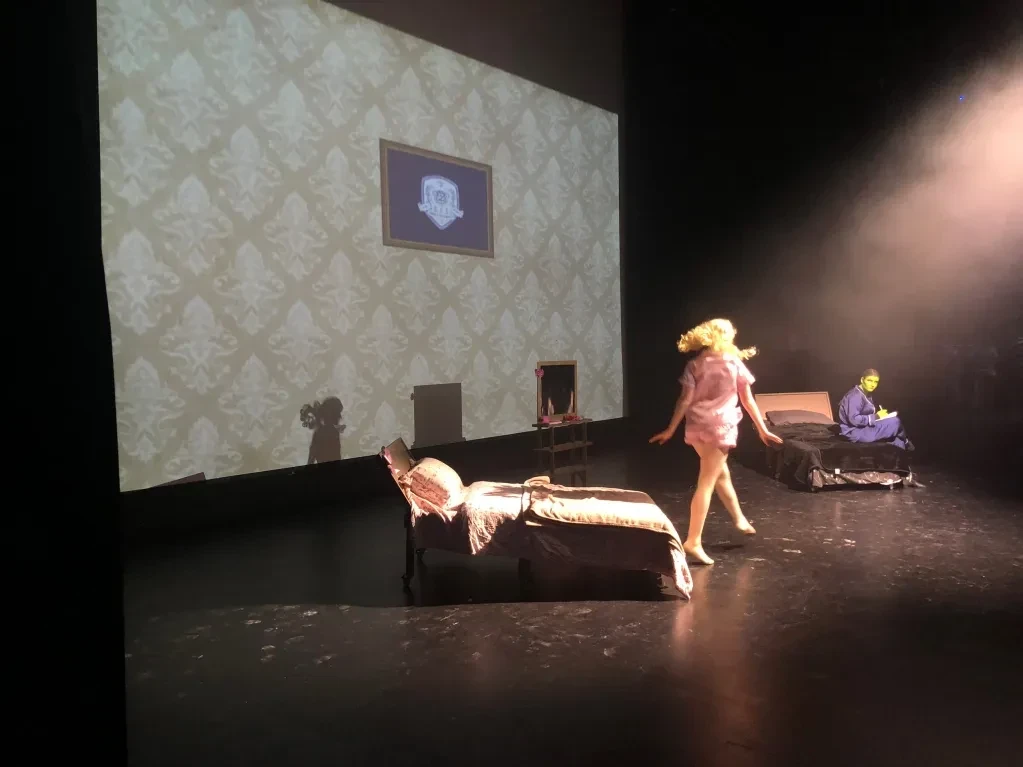Two performers on stage with ornate wallpaper projected backdrop