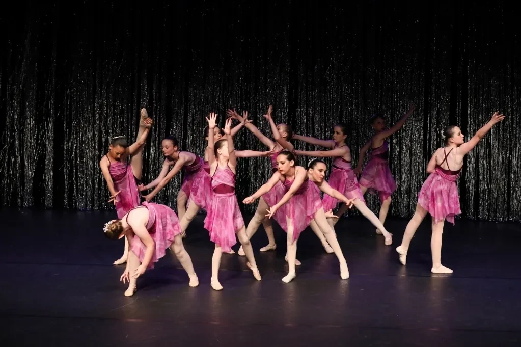 Group of dancers in pink lyrical dresses performing expressive contemporary routine on stage