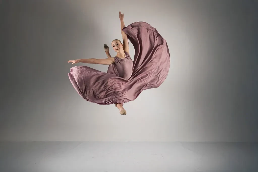 Dancer in mauve flowing dress mid-leap